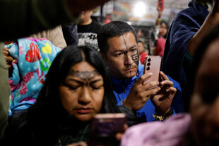 zwei Menschen mit indigenem Hintergrund schauen auf Smartphones