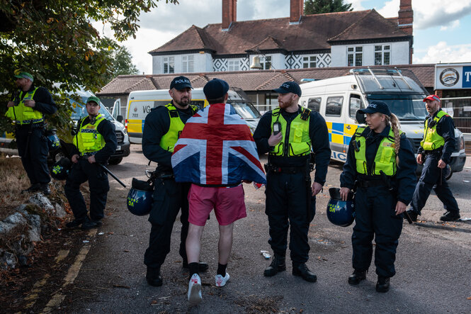 Polizeibeamte halten einen Mann mit einer Union-Jack-Flagge während einer Demonstration zurück
