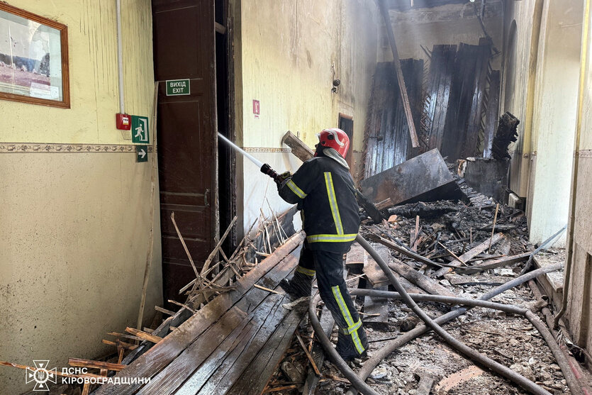 Ein Feuerwehrmann löscht einen Brand in einem teilweise zerstörten Gebäude