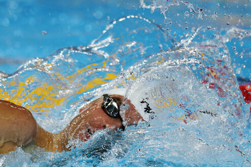 Bobby Finke holt beim Schwimmen Luft mit Blick Richtung Kamera