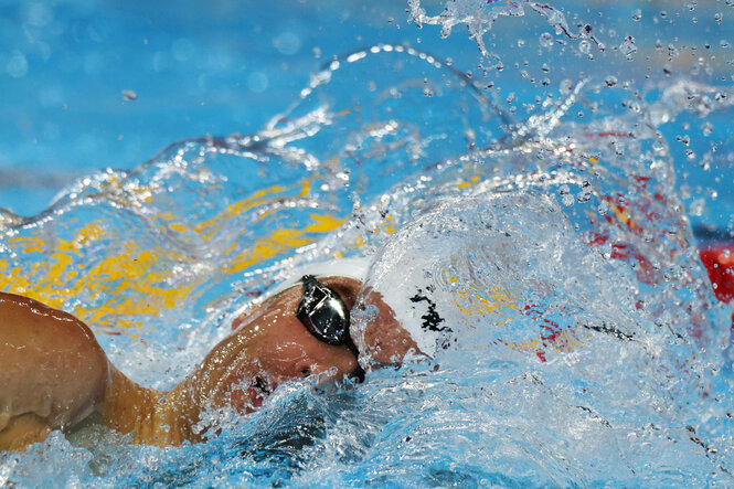 Bobby Finke holt beim Schwimmen Luft mit Blick Richtung Kamera