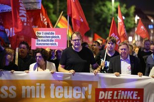 Demonstration, Sören Pellmann trägt mit anderen ein Plakat in der ersten Reihe mit dem Logo der Linken, hinter ihnen weitere DemonstrantInen mit Flaggen der Linken