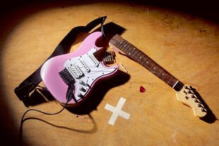 eine rosa Gitarre liegt zerbrochen auf dem Boden