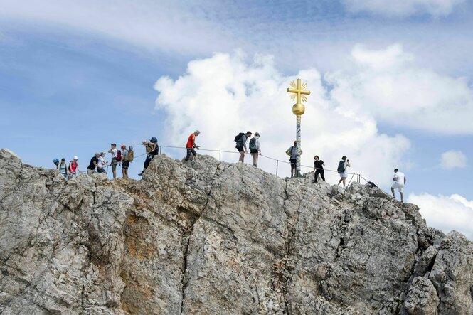 Viele Touristen am Gipfel der Zugspitze mit goldenem Gipfelkreuz