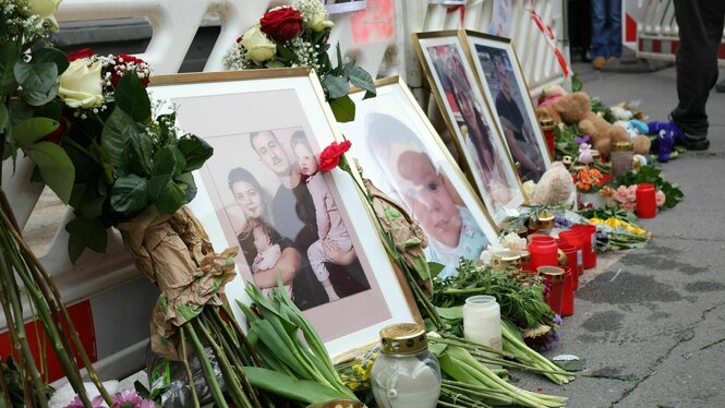 Fotos einer aus Bulgarien stammenden Familie stehen bei einer Mahnwache vor dem ausgebrannten Haus