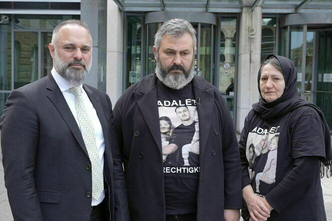 Drei Personen stehen nebeneinander vor einem Gebäude