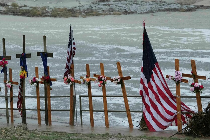 Vor dem Hintergrund des Guadalupe River stehen Kreuze und eine US-Flagge