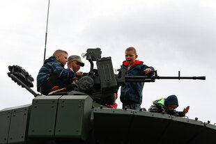 Kinder sitzen auf einem gepanzerten Fahrzeug an einer Kanone