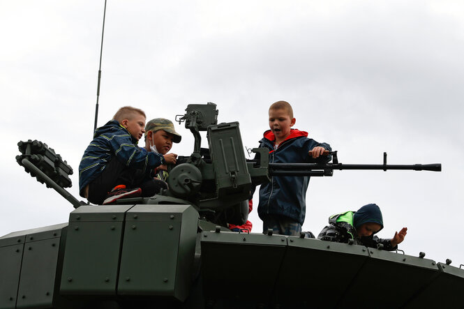 Kinder sitzen auf einem gepanzerten Fahrzeug an einer Kanone