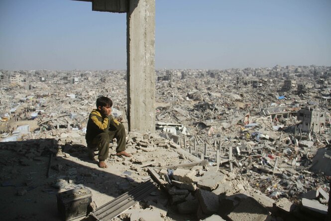 Ein Jugendlicher sitzt in einer Trümmerlandschaft in Gaza.