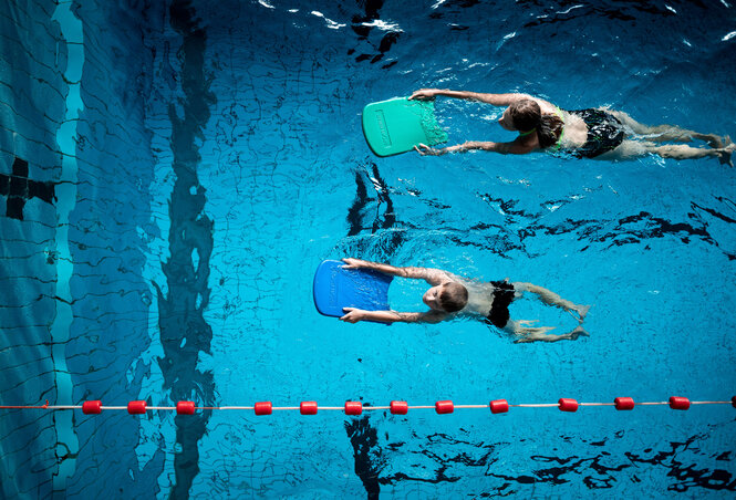 Zwei Kinder beim Schwimmunterricht mit Schwimmbrett