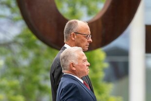 Ein großer und ein kleinerer Mann stehen nebeneinander: Bundeskanzler Friedrich Merz (CDU) und Abdullah II. Ibn Al-Hussein (vorne), König von Jordanien