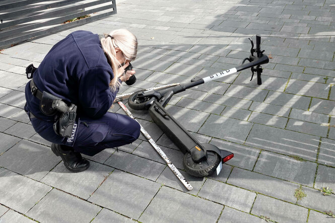 Eine Polizistin fotografiert einen am Boden liegenden schwarzen E-Scooter