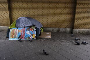 Zelt auf einem Bürgersteig, Tauben spazieren davor