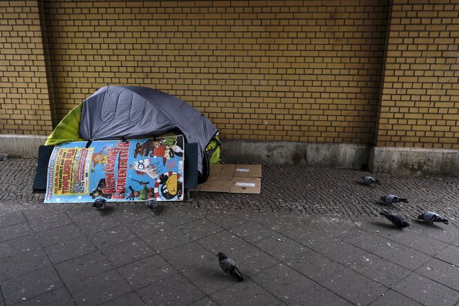 Zelt auf einem Bürgersteig, Tauben spazieren davor