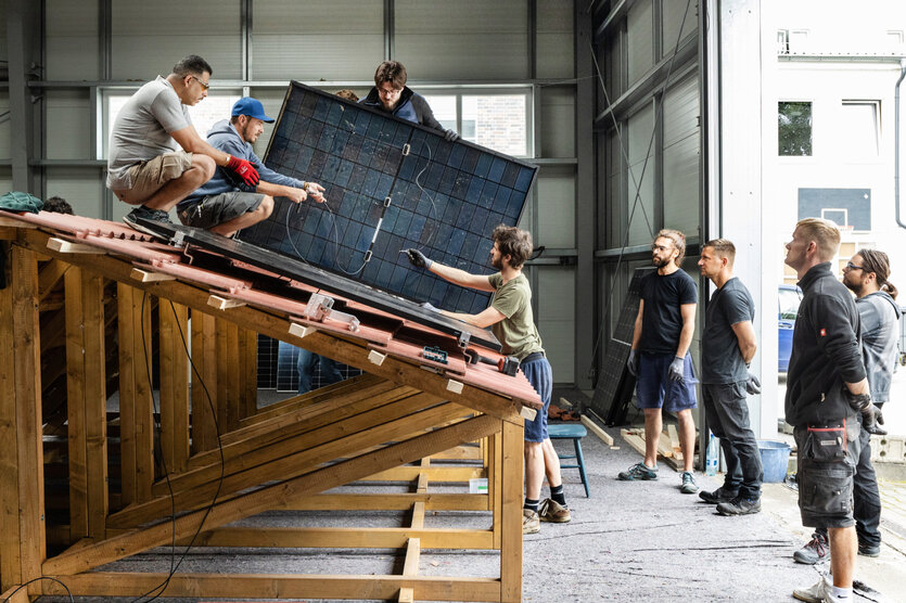 Mehrere Personen bastel an einem Solarmodul.