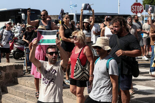 Propalästinensiche Demonstraten stehen am Hafen und halten Flaggenbilder und Fotos aus Gaza hoch