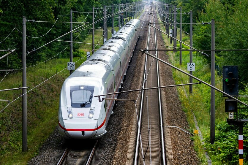 Ein ICE fährt auf der Bahnstrecke zwischen Berlin und Hamburg durch bewaldetes Gebiet an einem Signal vorbei.
