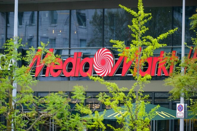 Das rote Logo von Mediamarkt vor dem grüne Bäume stehen