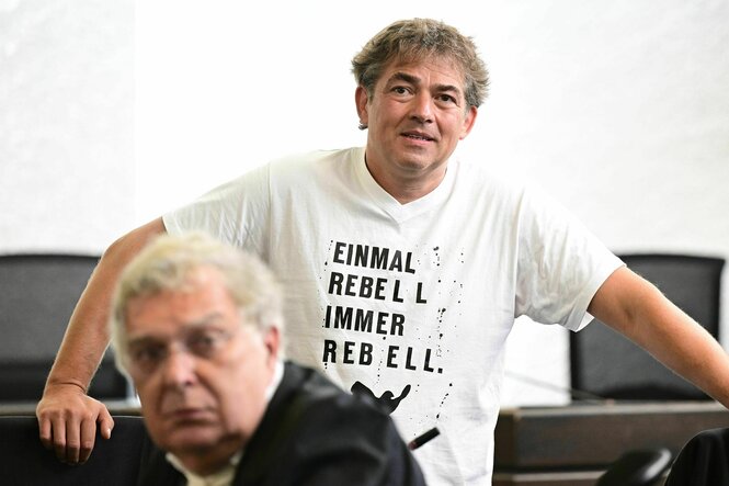 Michael Ballweg steht im Gerichtssaal vor ihm ein Anwalt, er trägt ein weißes T-Shirt mit dem Slogan: Einmal Rebell, immer Rebell
