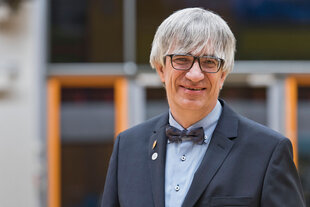 Der Physiker Metin Tolan steht vor einem Uni-Gebäude.
