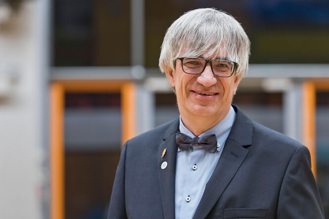 Der Physiker Metin Tolan steht vor einem Uni-Gebäude.