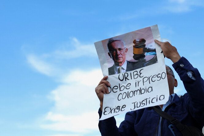 Ein Mann hält ein Plakat mit der Forderung: Ein Mann hält ein Plakat mit der Aufschrift „Uribe muss ins Gefängnis. Kolumbien fordert Gerechtigkeit“