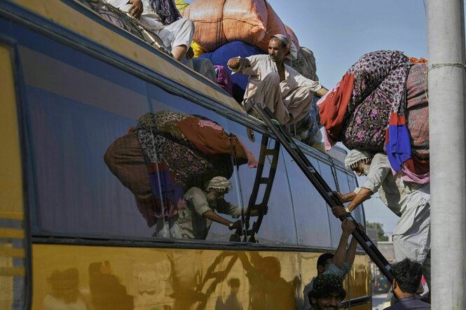 Menschen beladen das Dach von einem Bus mit Bündeln ihrer Habseligkeiten
