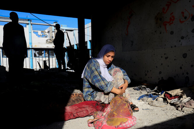 Eine Frau sitzt in einem ausgebombten Haus in Gaza