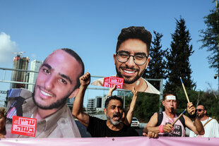 Menschen halten Bilder von Köpfen der Geiseln hoch