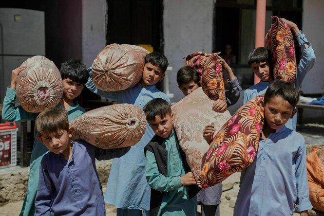 Sechs afghanische Jungs, die aus Pakistan abgeschoben wurden. Sie tragen Säcke und Kissen.
