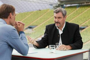 Zwei Männer sitzen sich an einem Tisch gegenüber und unterhalten sich