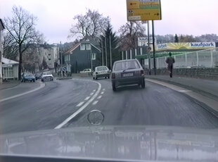 Straße mit Ortsschild und Autos