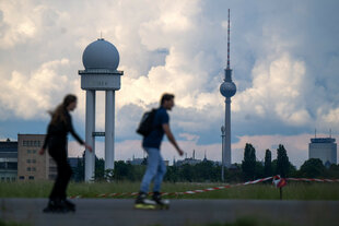 Zwei Inline-Skater fahren vor der Kulisse des Berliner Fernsehturms über das Tempelhofer Feld