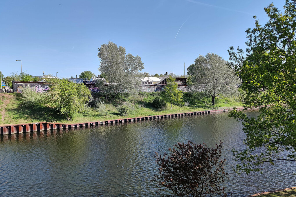 Gebäude hinter Bäumen an einem Kanal