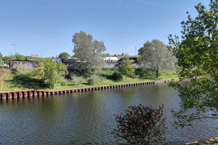 Gebäude hinter Bäumen an einem Kanal