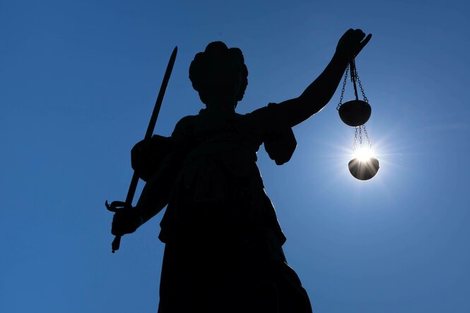 Die Silhouette der Justitia-Statue auf dem Römerberg in Frankfurt am Main im Gegenlicht