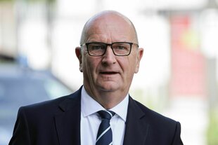 Ein Mann im Anzug schaut geradeaus in die Kamera