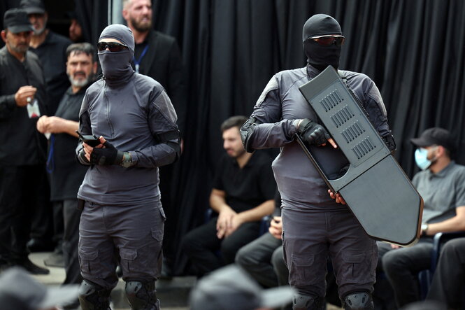 Zwei vermummte Personen tragen Waffen, die zur Abwehr von Drohnen eingesetzt werden