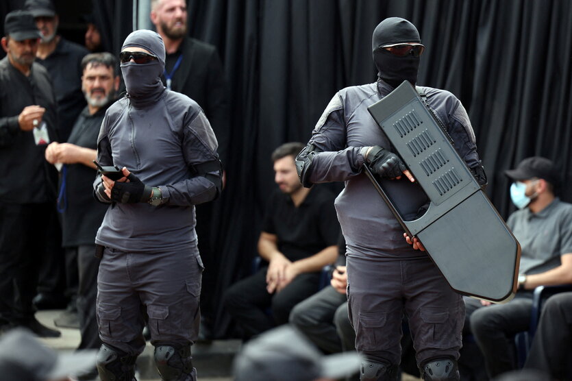 Zwei vermummte Personen tragen Waffen, die zur Abwehr von Drohnen eingesetzt werden