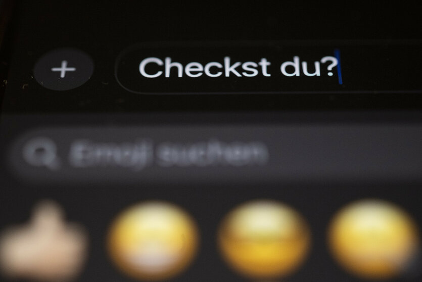Die Worte "Checkst du?" sind auf einem Smartphone zu sehen.