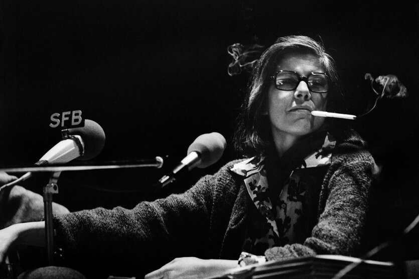 Susan Sontag sitzt hinter mehreren Mikrofonen.