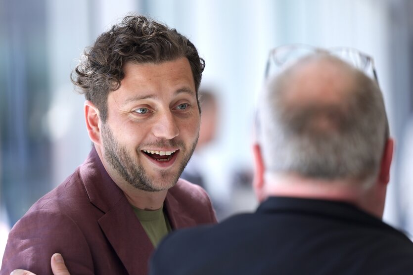 Zwei Personen sprechen miteinander, einer wird mit Gesicht gezeigt: Es ist der Grünen-Vorsitzende Felix Banaszak