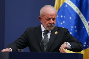 Ein Mann an einem Rednerpult schaut auf seine Armbanduhr