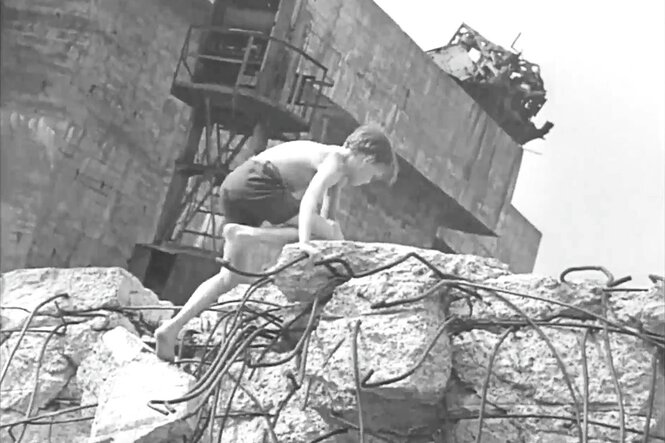 Ein Kind klettert über einen Trümmerhaufen vor einem Hochbunker.