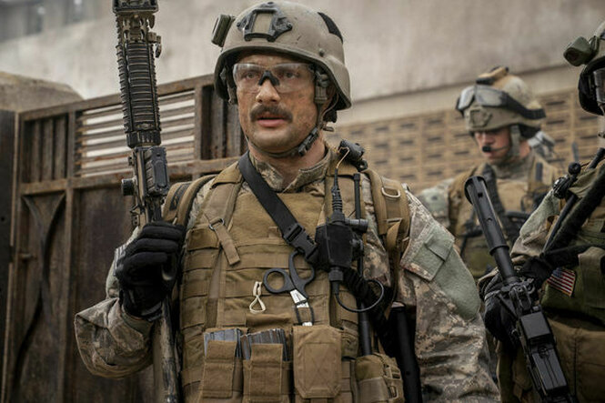 Ein Soldat mit Schutzbrille hält ein Gewehr hoch.