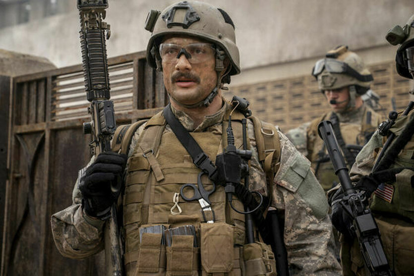 Ein Soldat mit Schutzbrille hält ein Gewehr hoch.