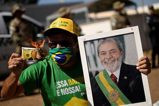 Ein Demonstrant zeigt eine brennende Dollarnotenattrappe mit dem Gesicht von US-Präsident Donald Trump und einem Bild des brasilianischen Präsidenten Luiz Inacio Lula da Silva