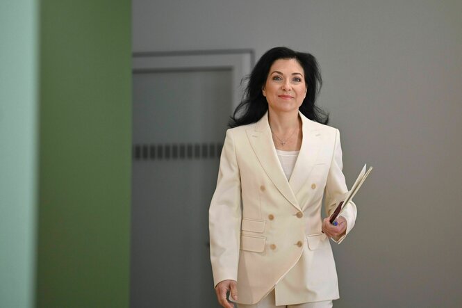 Eine Frau im weißen Jacket kommt auf die Kamera zugelaufen