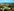 Luftbildbild zeigt im Vordergrund langgestreckte helle Gebäude, die von einer Mauer umgeben sind, dann Blick auf Häuser und dann das Meer